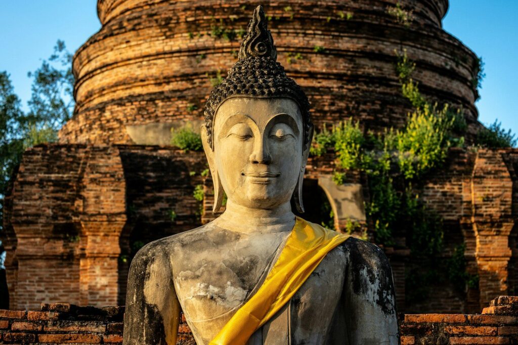 uma grande estátua de Buda sentada em frente a um prédio de tijolos