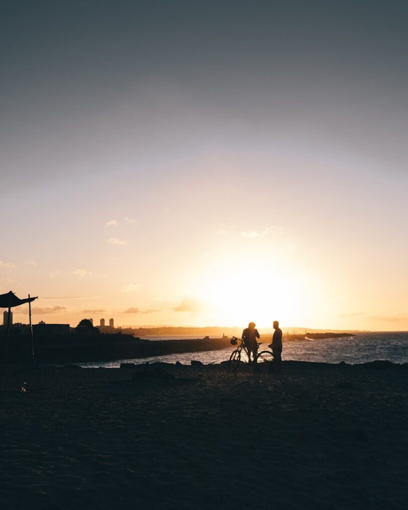 Silhueta de pessoas caminhando na praia durante o pôr do sol