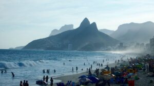 a beach with people and umbrellas with Ipanema in the background