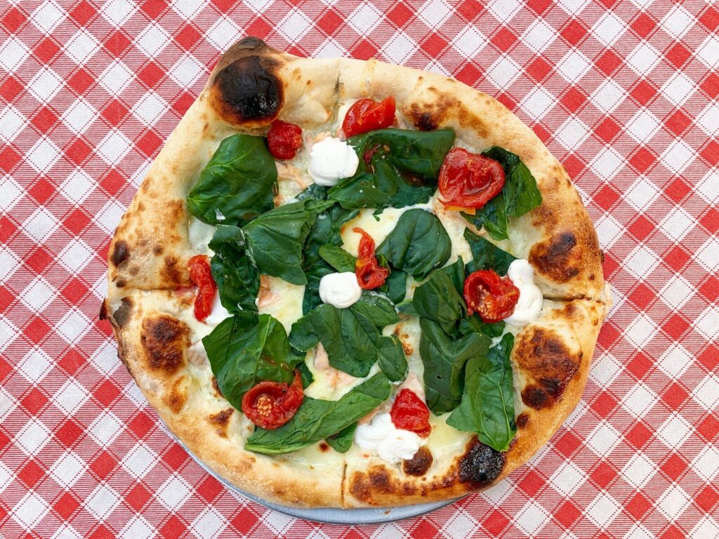 Pizza com folhas verdes em prato de cerâmica branca