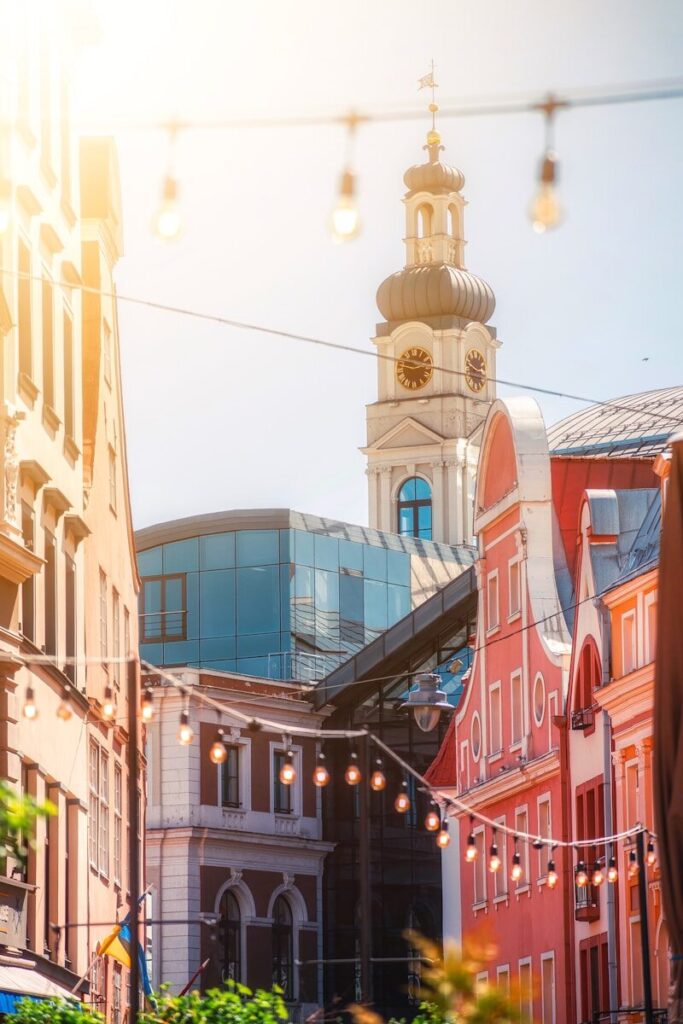 Uma rua da cidade com a torre de uma igreja ao fundo