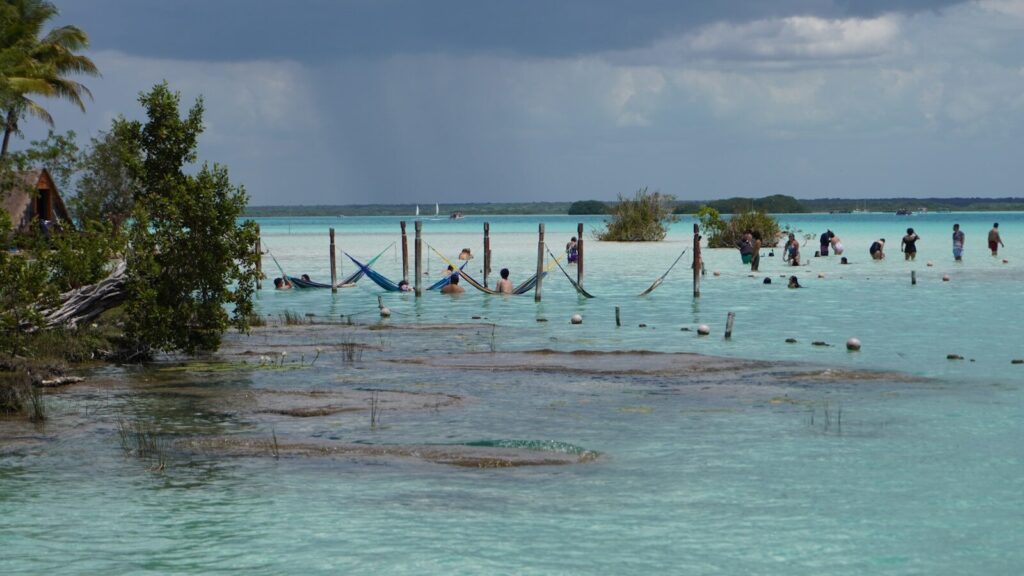 People relaxing in hammocks over turquoise water