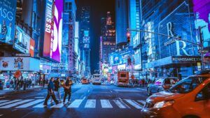 People crossing a street in Times Square, New York City, under bright neon signs