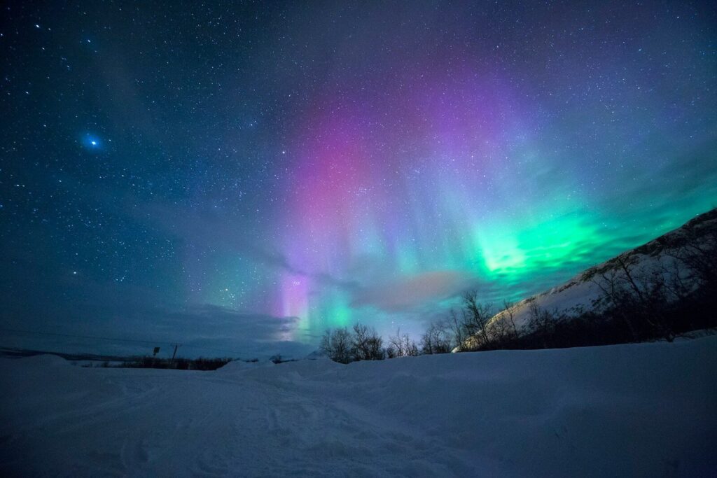 aurora boreal sobre montanha coberta de neve