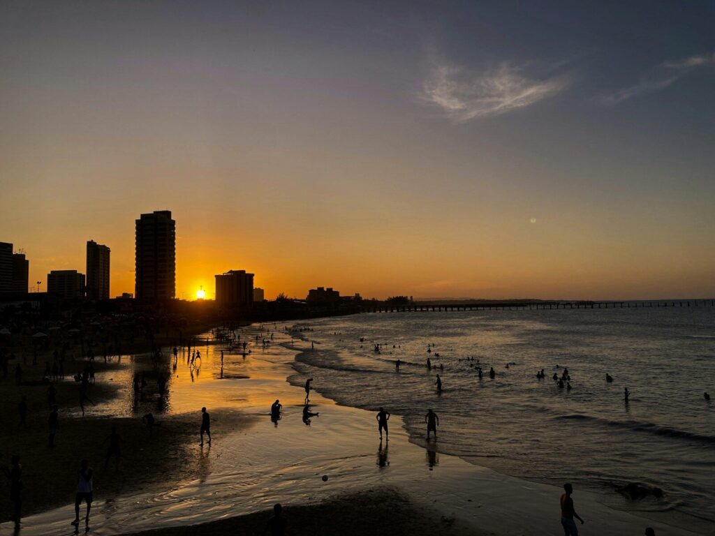 um grupo de pessoas em pé no topo de uma praia perto do oceano
