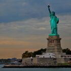 the statue of liberty stands in front of a body of water