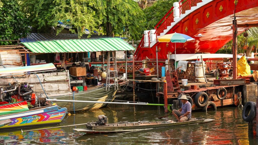 A man rows a boat in a bustling floating market