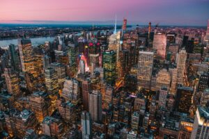 An aerial view of the Manhattan skyline at night with glowing office buildings