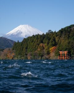 Mount Fuji seen across Lake Ashi in Hakone, with a red torii gate at the shoreline