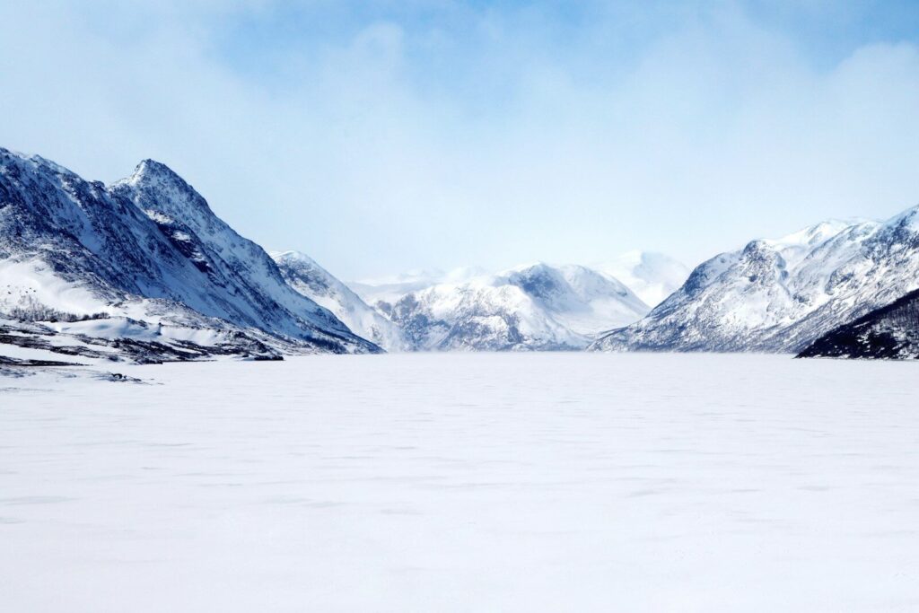 The frozen lake surface covered in winter snow beneath the mountains