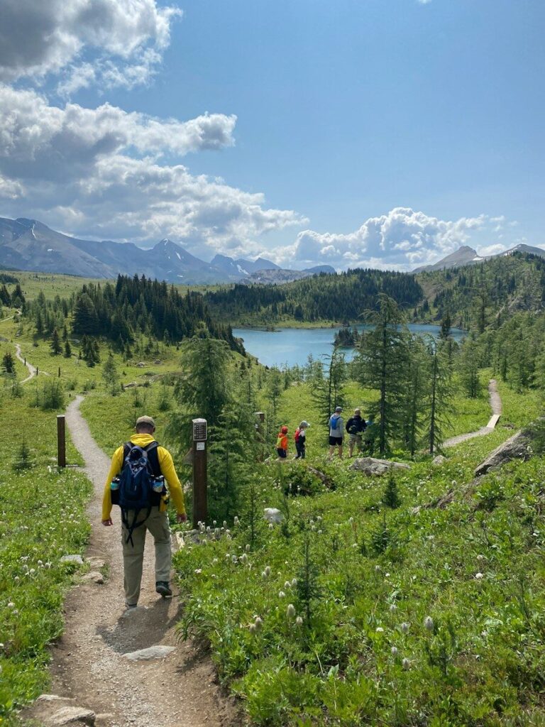 Hikers on an alpine trail overlooking a turquoise lake