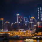 a city skyline at night with a bridge in the foreground