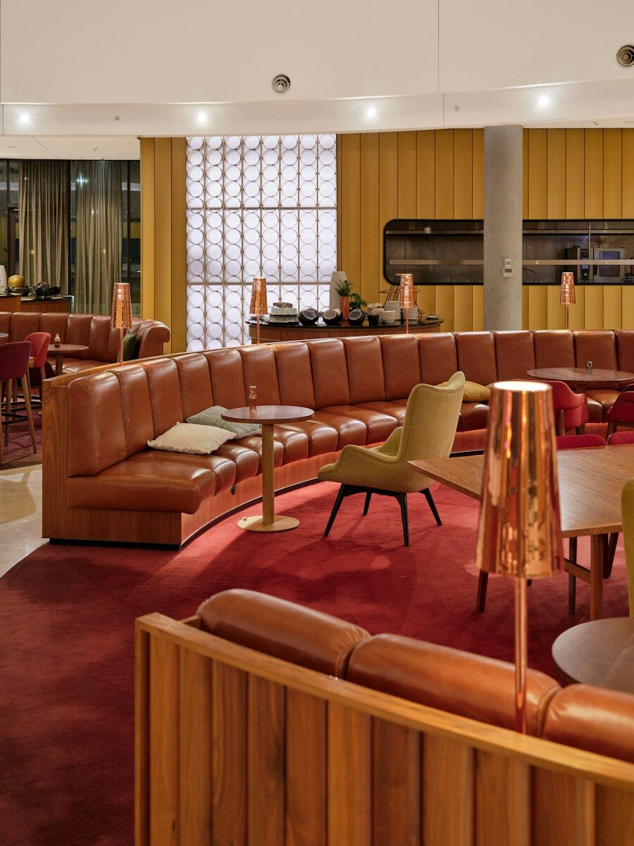 A quiet airport lounge with curved leather seating and warm light