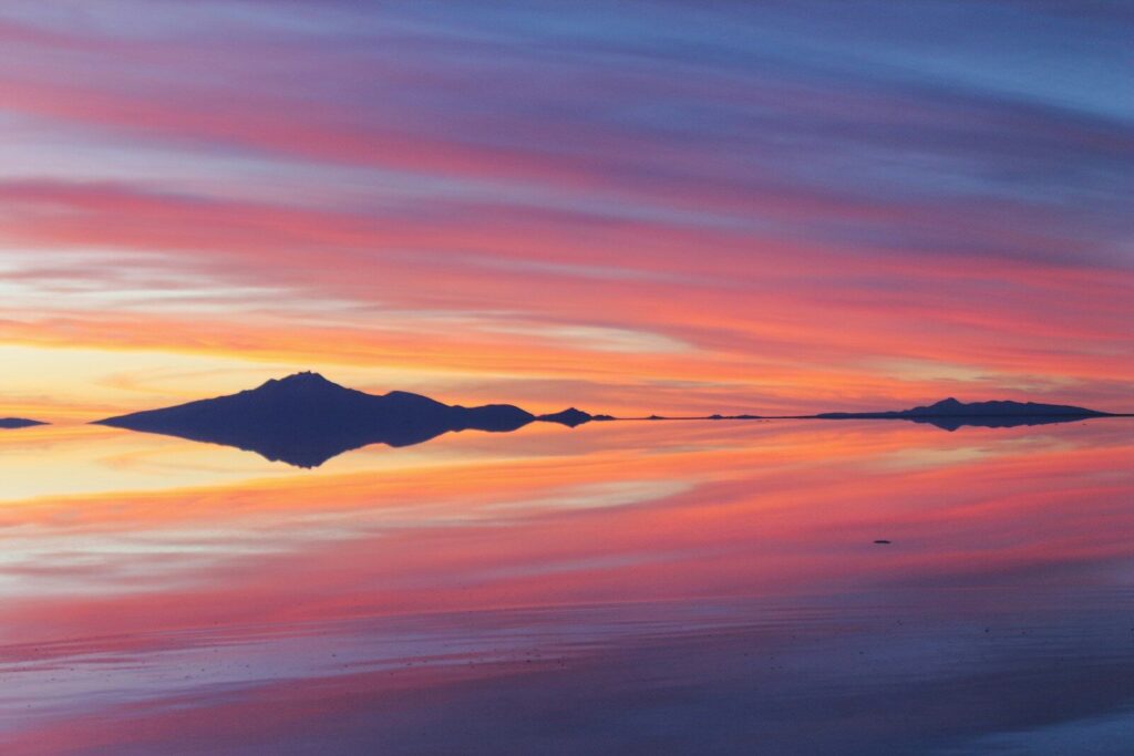 Pink and orange sunset colours reflected across the Salar de Uyuni
