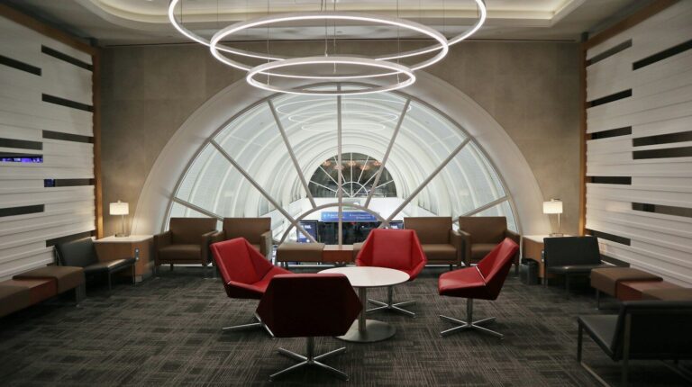 Red armchairs beneath an arched window in an airport lounge